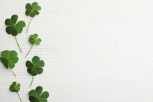 Clover Leaves On White Wooden Table, Flat Lay With Space For Text. St. Patrick's Day Symbol
