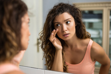 tired woman looking her eye bags in the bathroom.