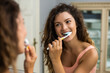 © inesbazdar - Beautiful woman brushing teeth in the bathroom.