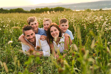 Wall Mural - Happy family on daisy field at the sunset having great time together