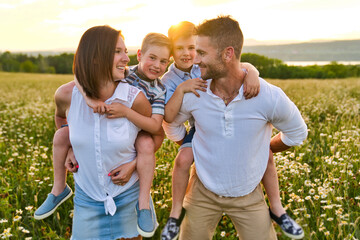 Wall Mural - Happy family on daisy field at the sunset having great time together