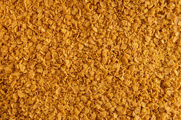 Abstract background of golden breadcrumbs replacement made from yellow gluten-free cornflakes. view from above texture top view