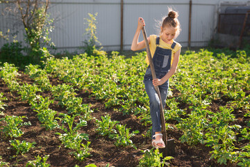 Wall Mural - beautiful teenage girl on the background of a green garden in summer digs with a shovel