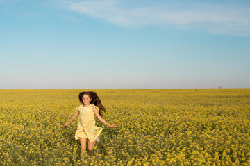 Wall Mural - portrait of a teenage girl in a yellow dress running across the field in summer