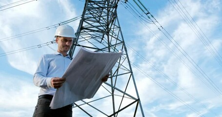 Wall Mural - an engineer studies modernization plans of a high-voltage line on paper drawings, when standing next
