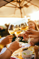 People clinking glasses with wine on the summer terrace of cafe or restaurant