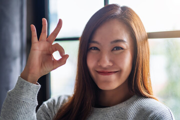 Closeup image of a beautiful young asian woman making and showing ok hand sign