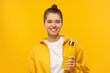 © Damir Khabirov - Happy girl in t-shirt and hoodie, holding reusable water bottle in hand, isolated on yellow background