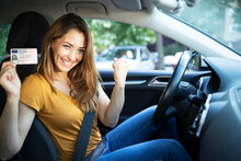 Car Interior View Of Woman With Driving License. Driving School. Young Beautiful Woman Successfully Passed Driving School Test. Female Smiling And Holding Driver's License.