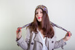 © papa - A beautiful fashionable woman in a light raincoat and bandana poses on a light background.