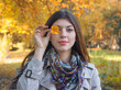 © papa - Portrait of a happy young woman with an autumn leaf at the eye.