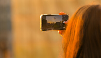 woman photographing with her smartphone the sunset in brussels belgium from garden of the mont des a