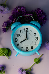 blue alarm clock with flowers on gray background