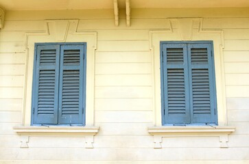 Sticker - Two windows with blue wooden blinds on a yellow building