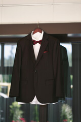 Sticker - Suit jacket hanging on a hanger with a boutonniere in place.