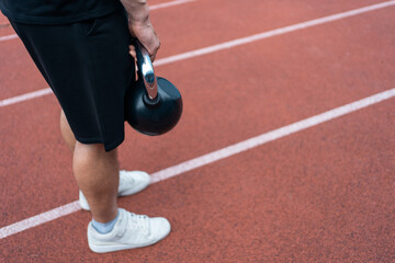 Wall Mural - young athlete has workout and doing sport exercises with kettlebell outdoor