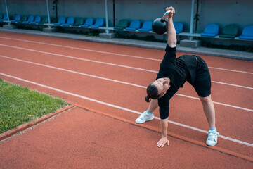 Wall Mural - young athlete has workout and doing sport exercises with kettlebell outdoor