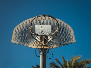 Wall Mural - Low angle shot of a basketball hoop against a blue sunny sky