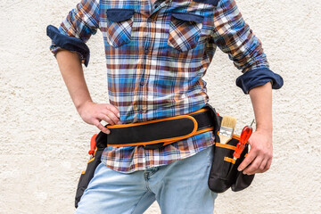 A construction worker dressed in a blue checked shirt and tool belt.