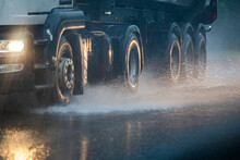 Rain Water Splash Flow From Wheels Of Heavy Truck Moving Fast In Daylight City With Selective Focus.
