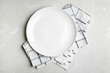© New Africa - Empty white plate and napkin on light grey marble table, flat lay