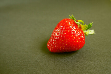 red juicy strawberry with a green leaf on an orange-black background