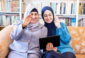 Wall Mural - Happy arabic mother and her daughter using technology together