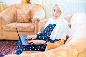 Wall Mural - Happy old arabic muslim woamn using technology while sitting on