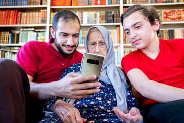 Wall Mural - Happy arabic muslim grand mother and her son sitting together on