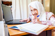 © Diya - Old women studying and writing using laptop and notebook