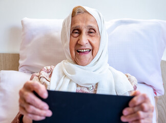 Wall Mural - Portrait of senior Arabic woman using electronic tablet at home