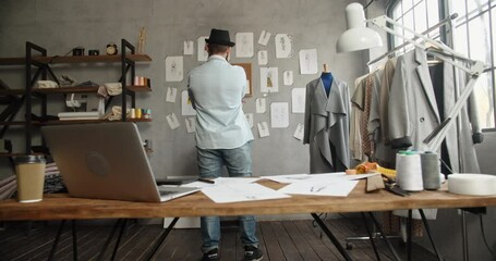 Wall Mural - Bearded hipster fashion designer is wandering around his office, looking for inspiration for new collection - fashion, small business concept 4k footage