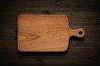 Hand-made cherry wood cutting board on the darkened wooden tabletop