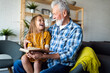 Happy little girl with grandfather reading story book at home