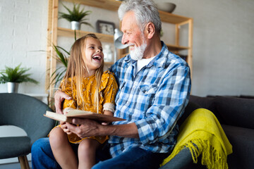 Sticker - Happy little girl with grandfather reading story book at home