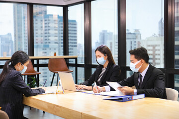 Wall Mural - Asian people working together in co-working space following social distancing and new normal policy by wearing facial mask in the business office workplace during covid-19 outbreak