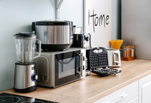 Different Household Appliances On Table In Kitchen