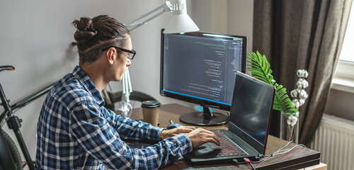 Male programmer is writing program code on a laptop at home. The concept of software development