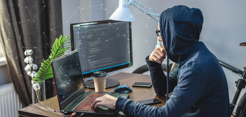 Hacker in a hood are programming virus code on a laptop. The concept of Internet fraud and personal data hacking