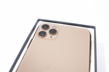 gold-colored smartphone with three cameras on a white background