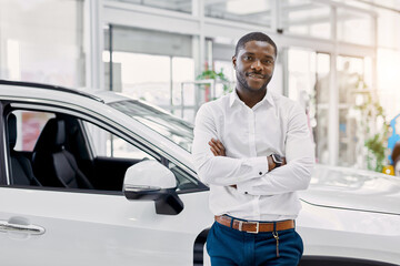 portrait of smiling afro man in white shirt, he stands next to new car, look at camera.