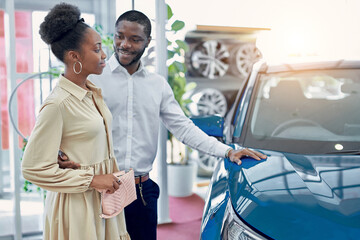 portrait of beautiful african married couple came in dealership to buy their first family car. happy customers make purchase, choose