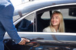 © Roman - african taxi driver opening the door of car, help female client to get out of car. in luxurious executive car, business lady