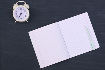 open notebook and clock on a gray school background. Top view, place for inscription