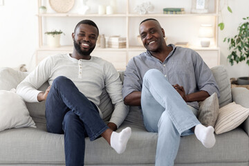 Like Father Like Son. Happy Man Sitting In Similar Pose With Dad