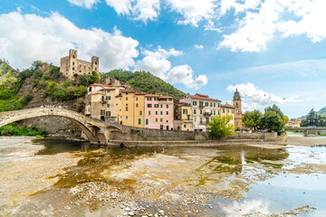 Wall Mural - View across the Nevia River of the Saint Anthony Church, arched bridge and the medieval Castle fortress overlooking the Ligurian city of Dolceacqua, Italy,