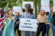 © Roman - portrait of black American guy during BLM manifestation, young afro man holds poster with 'I am not a criminal' description