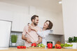 © ViDi Studio - Laughing young couple two friends guy girl in casual clothes preparing vegetable salad cooking food in light kitchen at home. Dieting family healthy lifestyle concept. Mock up copy space. Hugging.