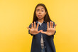 © khosrork - No, I'm afraid! Portrait of scared girl in denim shirt standing with raised hands stop gesture, panicking looking frightened of danger, phobia. indoor studio shot isolated on yellow background