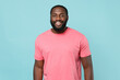 © ViDi Studio - Smiling young african american man guy in casual pink t-shirt posing isolated on pastel blue background studio portrait. People sincere emotions lifestyle concept. Mock up copy space. Looking camera.